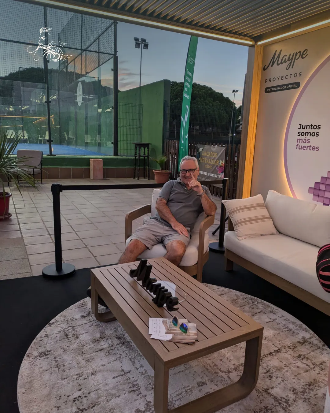 Zona de descanso con sofás junto a una pista de pádel durante el torneo de pádel solidario del Club La Barrosa